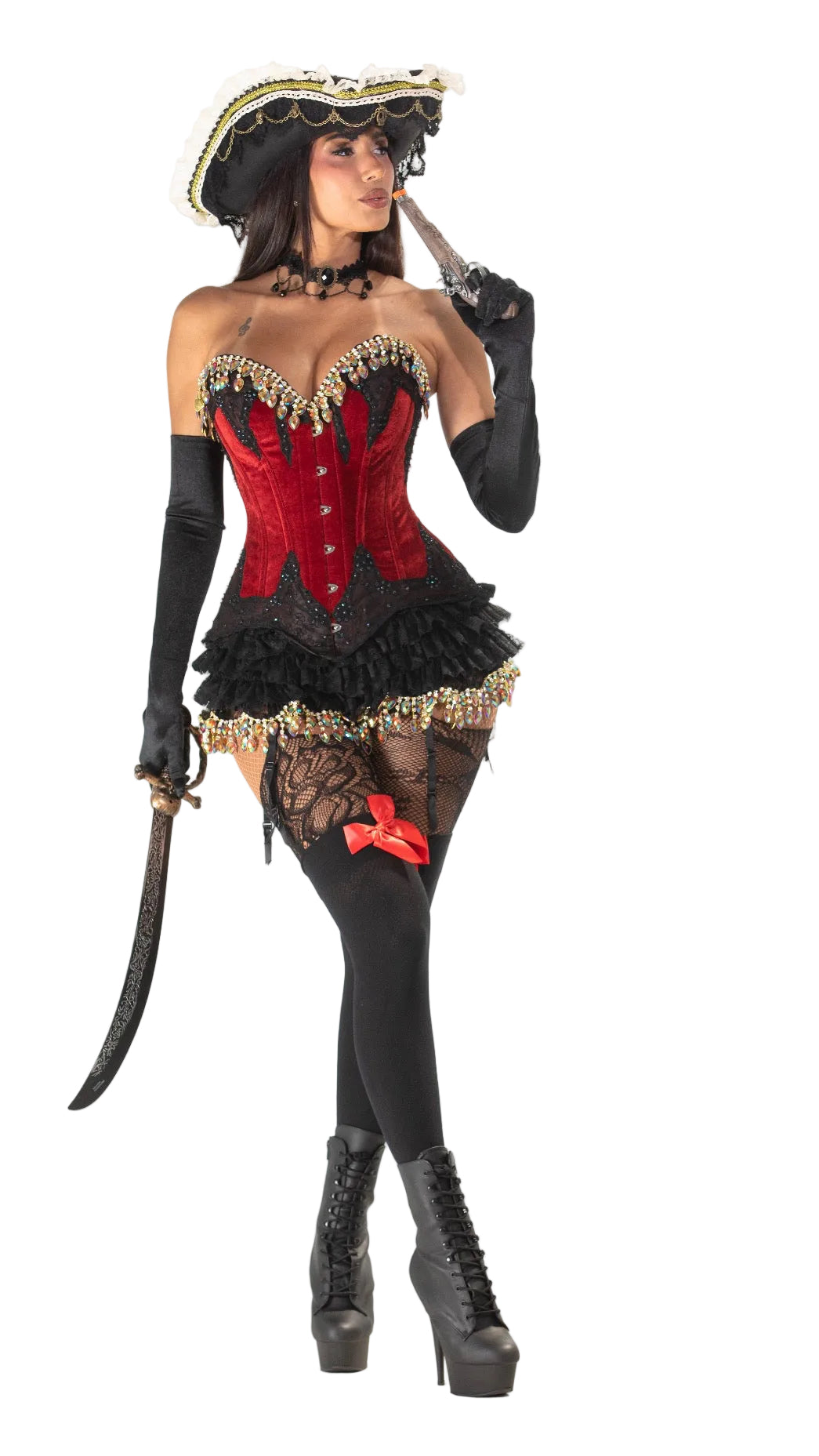 A woman modeling a pirate costume on a white studio background, wearing a red and black corset-style top with gold trim, a black ruffled skirt, black gloves, black fishnet stockings, a black hat with gold trim, thigh-high stockings, and black platform boots, while holding a sword.